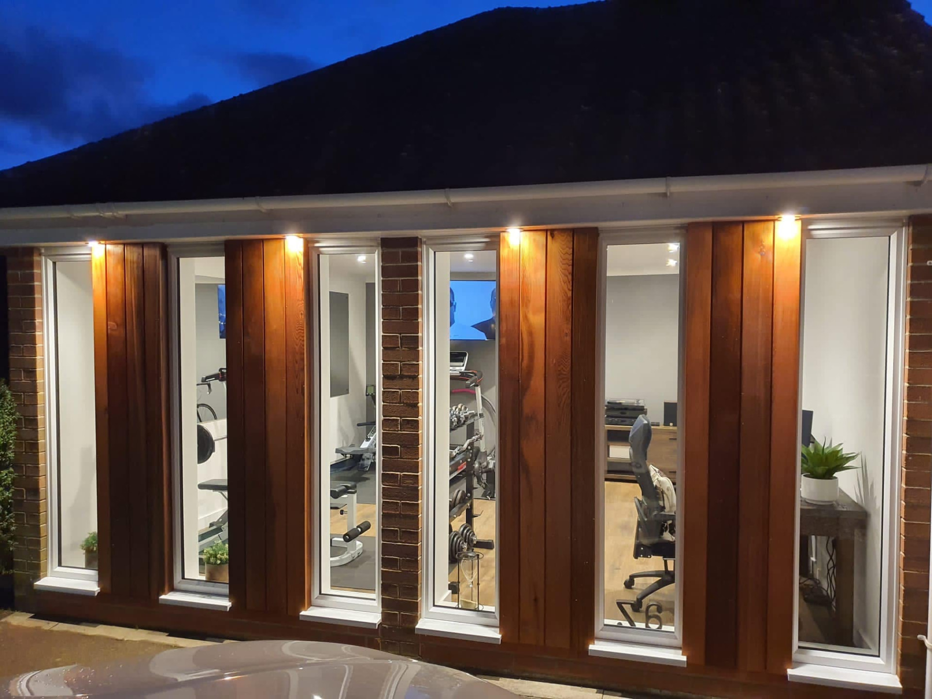Garden room extension at dusk with timber cladding and full-height glazing