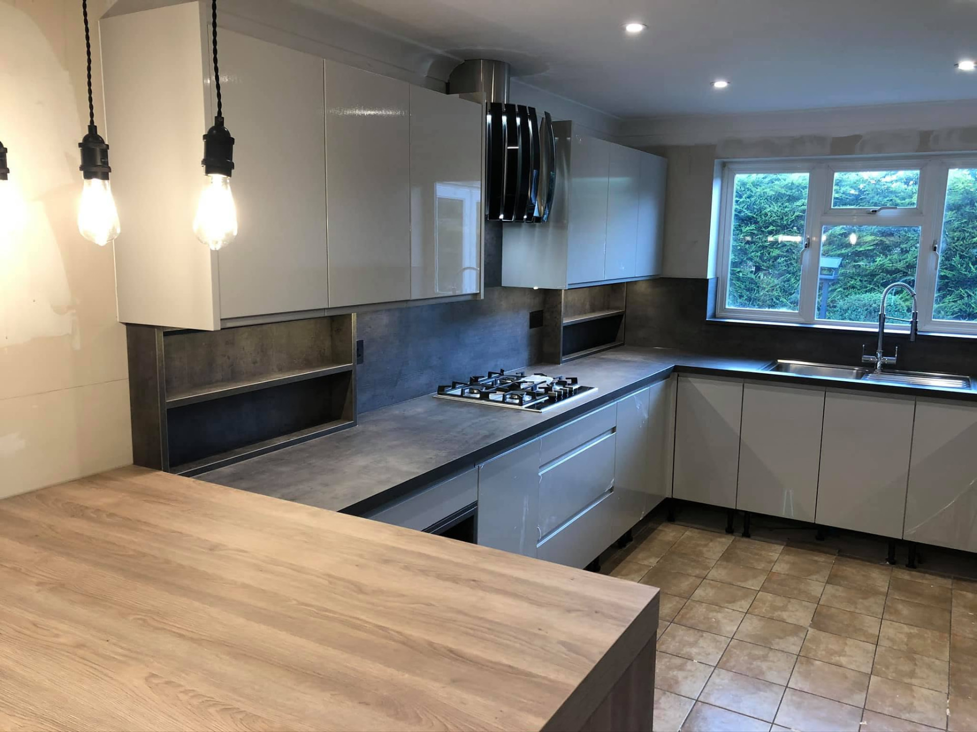 Fitted kitchen with gloss cabinets, worksurfaces and pendant lighting